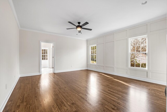 interior space with ornamental molding, wood finished floors, a ceiling fan, and a decorative wall