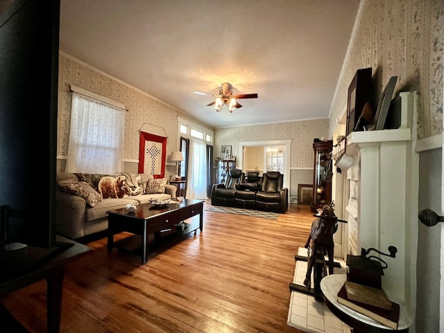 living area featuring wainscoting, crown molding, hardwood / wood-style floors, and wallpapered walls