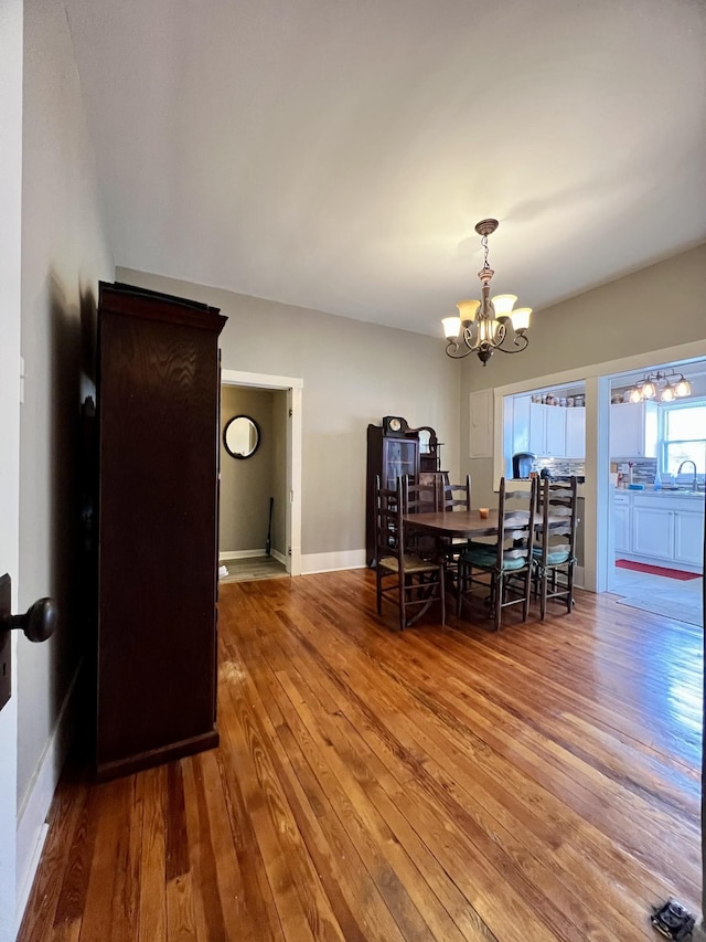 dining space featuring baseboards, a notable chandelier, and light wood finished floors