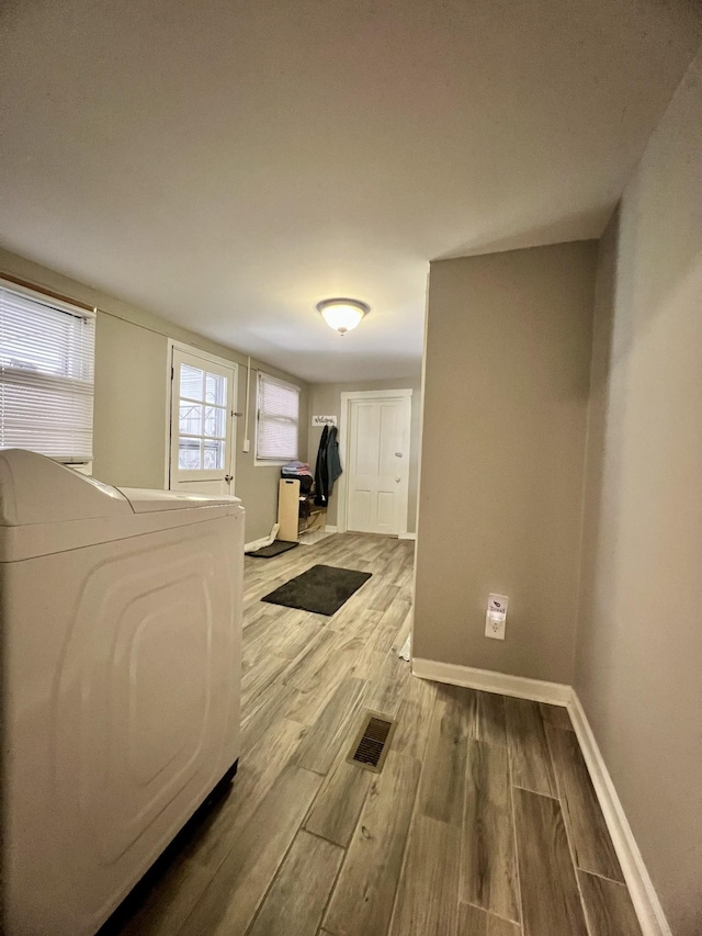 interior space with laundry area, washer / clothes dryer, wood finished floors, and baseboards