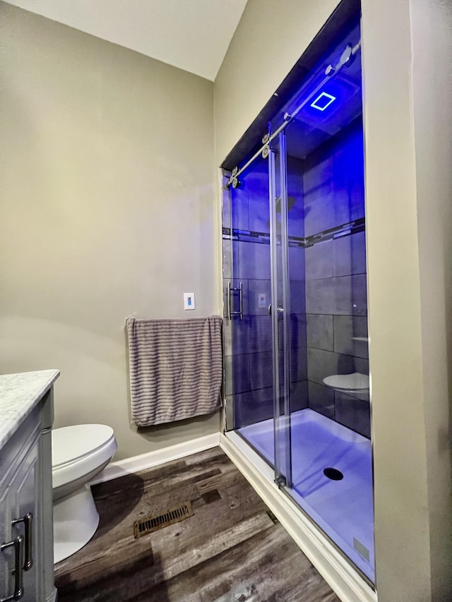 bathroom featuring toilet, wood finished floors, visible vents, vanity, and a shower stall