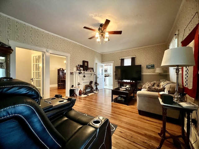 living area featuring crown molding, wood finished floors, a ceiling fan, and wallpapered walls