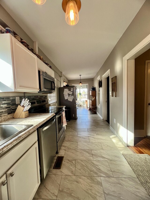 kitchen featuring visible vents, white cabinets, stainless steel appliances, light countertops, and backsplash