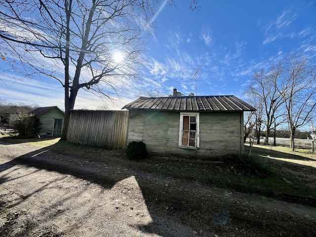 view of side of home with a chimney, metal roof, and an outdoor structure