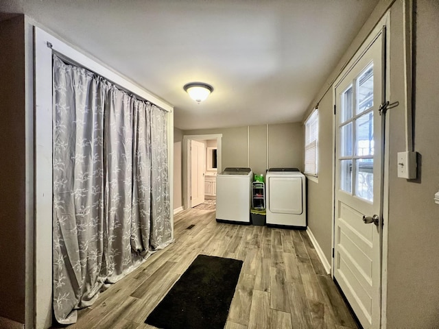 clothes washing area featuring laundry area, separate washer and dryer, wood finished floors, and baseboards