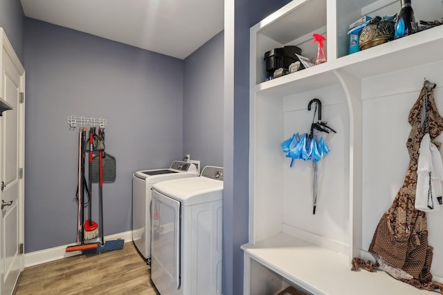 clothes washing area with light wood-type flooring, laundry area, baseboards, and washer and clothes dryer