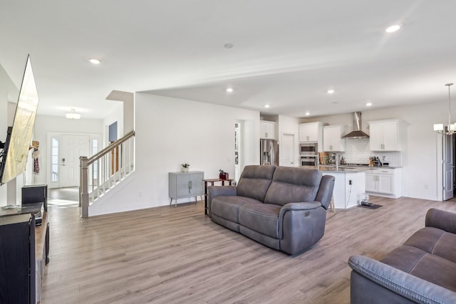 living room featuring stairs, light wood-type flooring, and recessed lighting