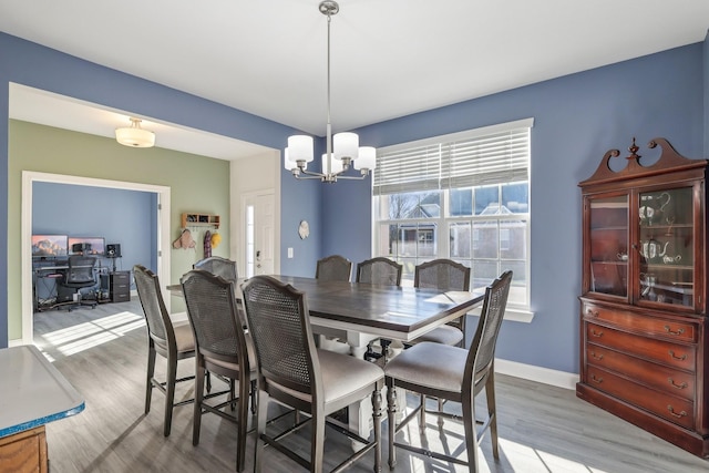 dining area with light wood-style flooring, a chandelier, and baseboards