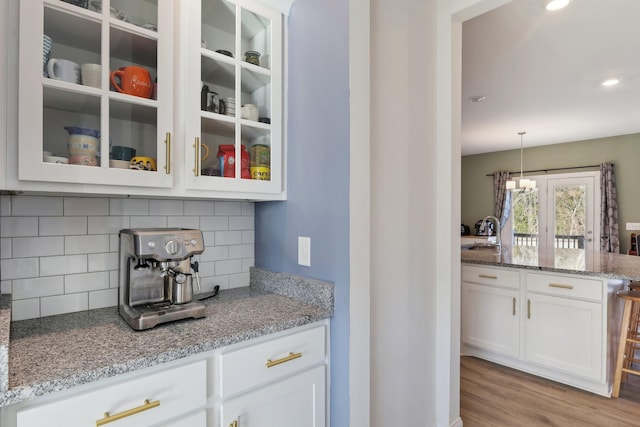 kitchen with glass insert cabinets, white cabinets, a sink, and light stone countertops