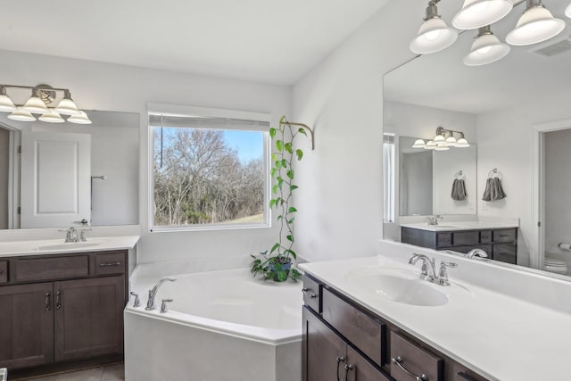 full bath featuring a bath, two vanities, a sink, and visible vents