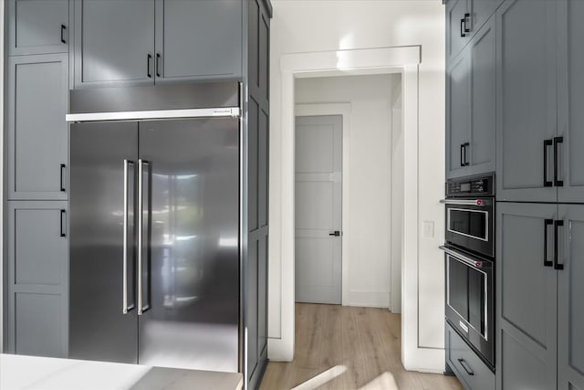105 Stillwind Ct, Nolensville, TN 37135 - kitchen featuring baseboards, light countertops, stainless steel built in refrigerator, dobule oven black, and light wood finished floors