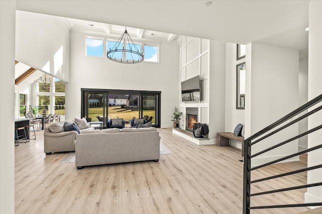 105 Stillwind Ct, Nolensville, TN 37135 - living area with a lit fireplace, light wood-style floors, a high ceiling, and a notable chandelier