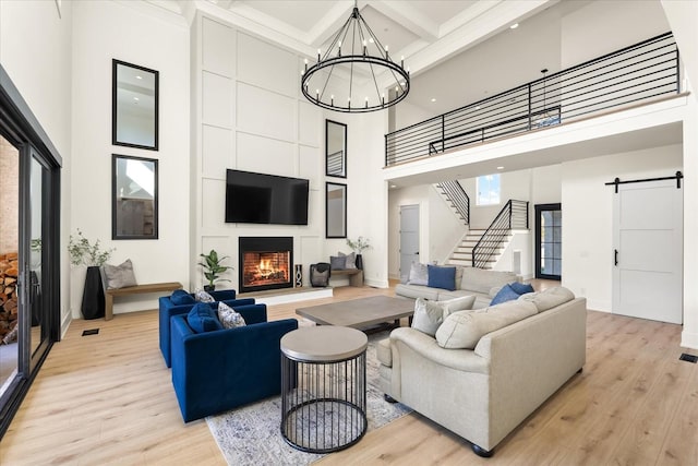 105 Stillwind Ct, Nolensville, TN 37135 - living room with a barn door, light wood-type flooring, a notable chandelier, and a towering ceiling