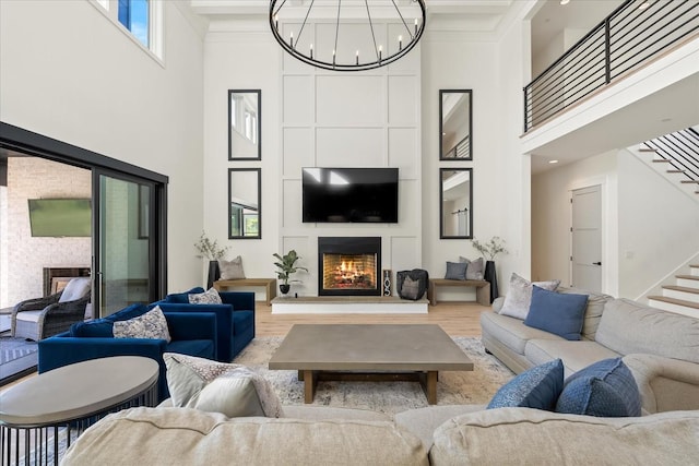 105 Stillwind Ct, Nolensville, TN 37135 - living room featuring a lit fireplace, a chandelier, a high ceiling, stairs, and wood finished floors