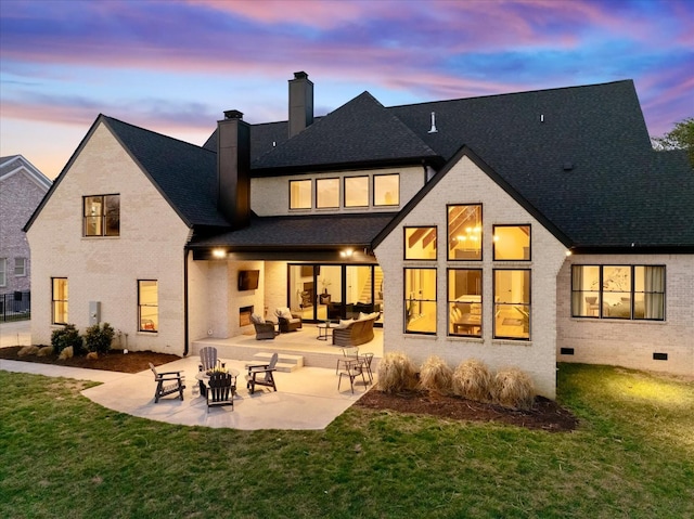 105 Stillwind Ct, Nolensville, TN 37135 - back of house at dusk featuring an outdoor living space, a yard, a patio area, brick siding, and a chimney