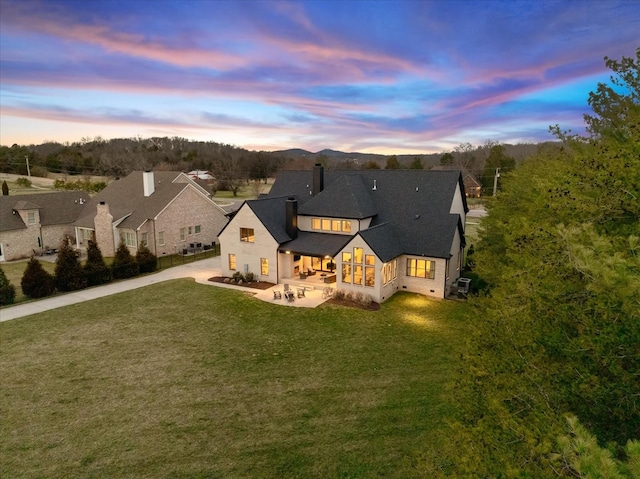 105 Stillwind Ct, Nolensville, TN 37135 - back of house at dusk with a patio, driveway, roof with shingles, and a lawn