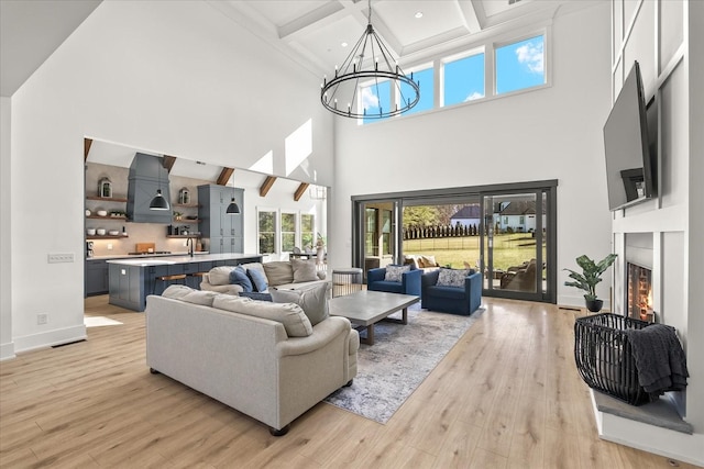 105 Stillwind Ct, Nolensville, TN 37135 - living area featuring light wood-style flooring, a towering ceiling, a warm lit fireplace, a chandelier, and beam ceiling