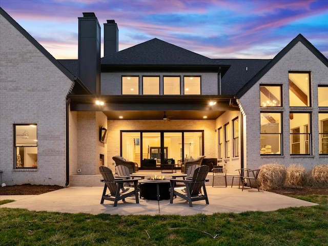 105 Stillwind Ct, Nolensville, TN 37135 - back of house at dusk featuring a chimney, a ceiling fan, an outdoor living space with a fire pit, a patio area, and brick siding