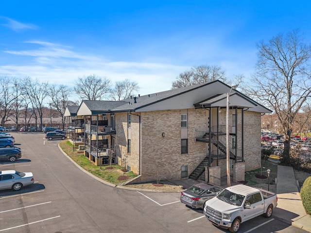 view of building exterior featuring stairs and uncovered parking