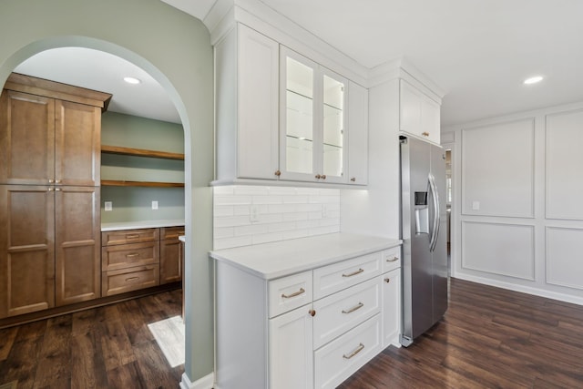 kitchen with dark wood finished floors, light countertops, decorative backsplash, white cabinets, and stainless steel fridge with ice dispenser