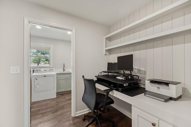 office featuring washer / clothes dryer, a sink, baseboards, and wood finished floors