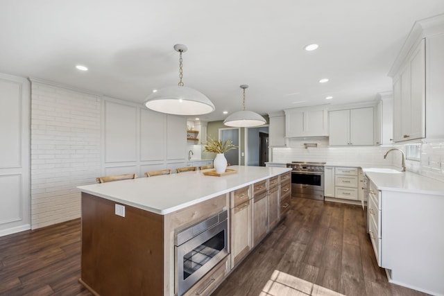 kitchen featuring appliances with stainless steel finishes, a center island, dark wood-type flooring, and a sink