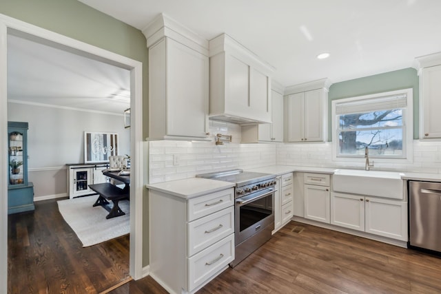 kitchen featuring appliances with stainless steel finishes, light countertops, a sink, and dark wood-style floors