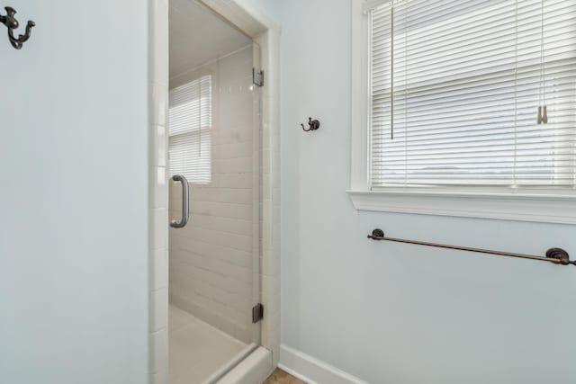 bathroom with a shower stall and baseboards