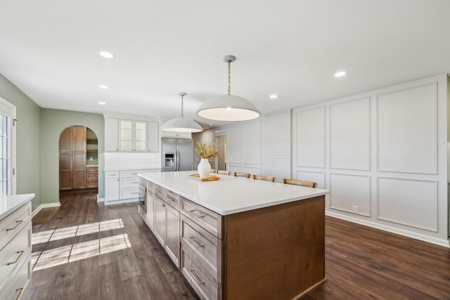 kitchen with a decorative wall, dark wood-type flooring, and built in fridge