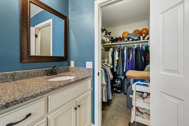 bathroom featuring a walk in closet and vanity