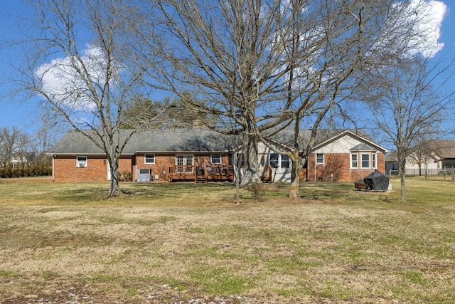 ranch-style home featuring brick siding, a deck, and a front yard