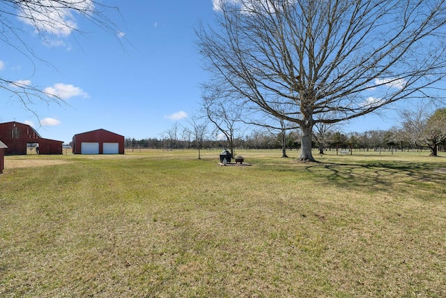 view of yard featuring driveway, a garage, and an outdoor structure