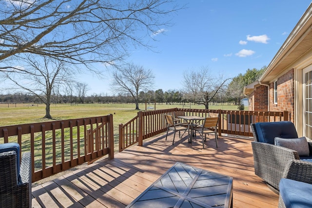 deck with a yard, outdoor dining space, and a rural view