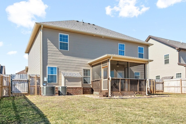 back of house featuring a sunroom, a gate, a lawn, and central AC