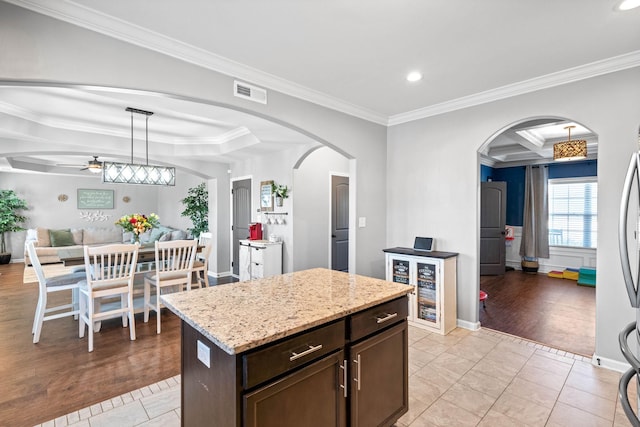 kitchen featuring arched walkways, coffered ceiling, visible vents, open floor plan, and dark brown cabinets