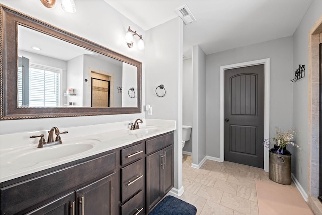 bathroom with visible vents, a sink, toilet, and double vanity