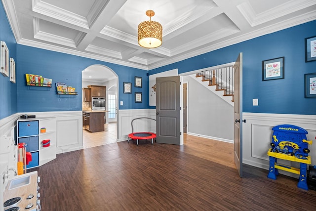 rec room with arched walkways, coffered ceiling, wainscoting, wood finished floors, and beamed ceiling