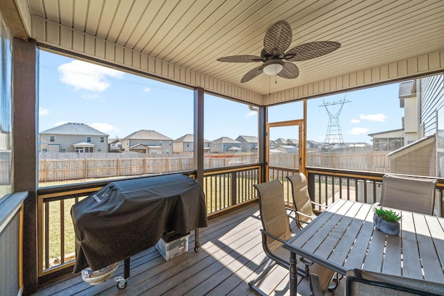 sunroom / solarium featuring a ceiling fan, a residential view, wood ceiling, and plenty of natural light