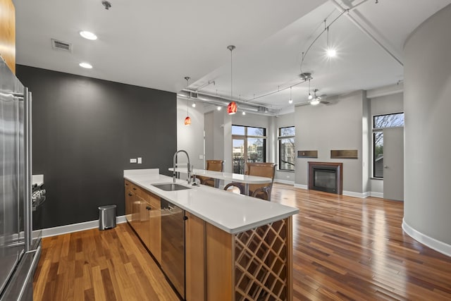 kitchen featuring visible vents, a glass covered fireplace, a sink, a peninsula, and hardwood / wood-style flooring