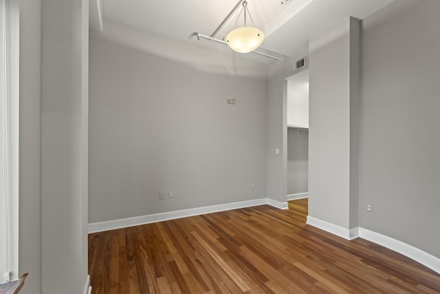 unfurnished room with wood finished floors, visible vents, and baseboards