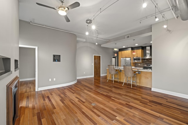 living area with a ceiling fan, rail lighting, visible vents, and wood finished floors