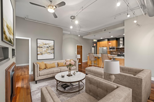 living area featuring visible vents, a ceiling fan, track lighting, wood finished floors, and baseboards