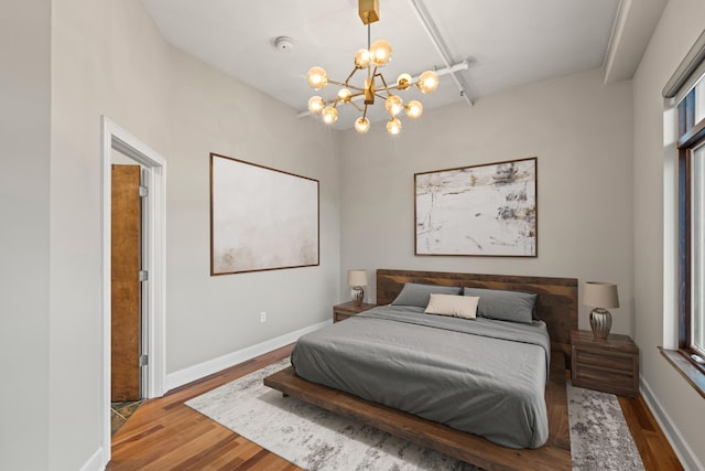 bedroom with a notable chandelier, wood finished floors, and baseboards