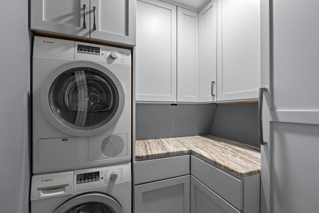 clothes washing area featuring stacked washer and clothes dryer and cabinet space