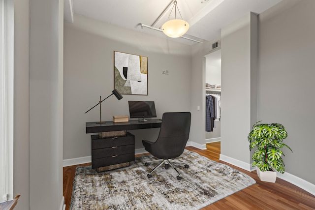 office space featuring visible vents, baseboards, and wood finished floors