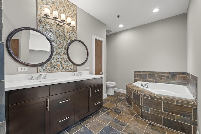 bathroom featuring double vanity, stone finish floor, a sink, and a bath