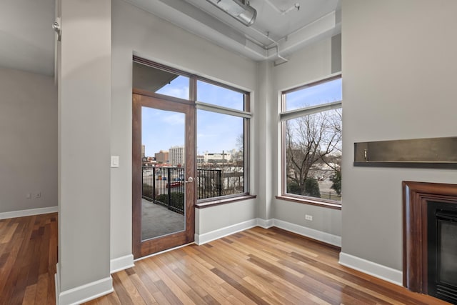 interior space with baseboards, hardwood / wood-style flooring, a city view, a fireplace, and track lighting