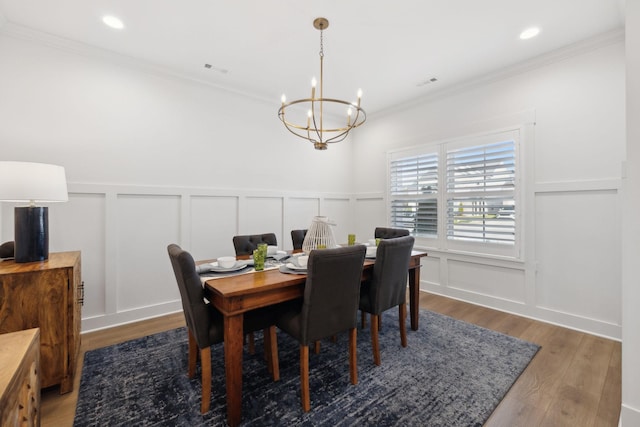 dining area with a chandelier, a decorative wall, wood finished floors, and ornamental molding