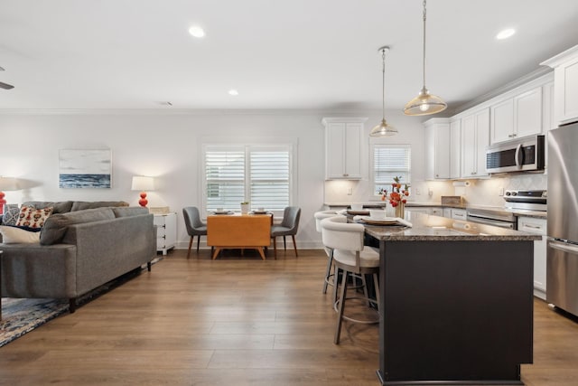 kitchen featuring dark wood finished floors, a breakfast bar area, decorative backsplash, appliances with stainless steel finishes, and a kitchen island