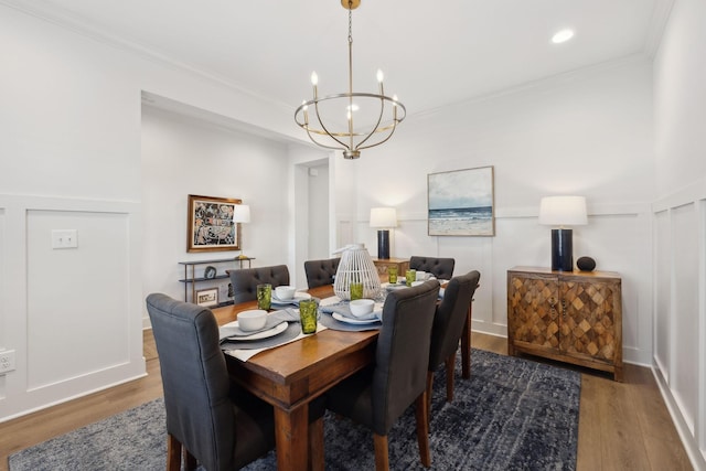 dining room featuring a notable chandelier, wood finished floors, and a decorative wall